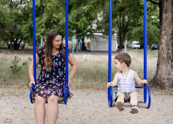 stock image Mom swinging her baby boy in swing outdoor. Mother and her child having fun together outdoor. Happy family concept