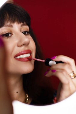 Güzel bir kadının portresi, dudaklarını kırmızı rujla boyuyor, aynaya bakıyor.