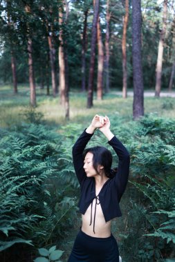 Ormandaki eğrelti otunda yaşayan Asyalı bir kadının romantik portresi. Sanat kadını doğal makyajı doğada dinleniyor. Yeşil eğrelti otları