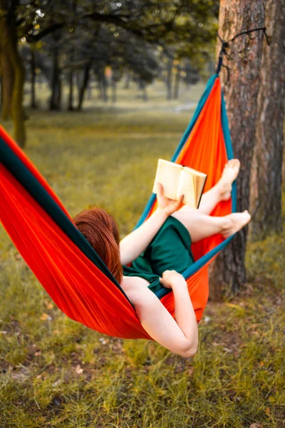 Hamakta kitap okuyan güzel sarışın kız. Doğa ön kapılarında güzel bir kadın, boş bir yaşam tarzı portresi. Kadın ormanda dinleniyor. Yaz kampında turizm. Hobi