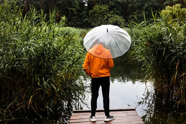 Visszapillantás Egy Fiatalemberre Narancssárga Esőkabátban Esernyővel Kezében Amint Egy Fából — Stock Fotó