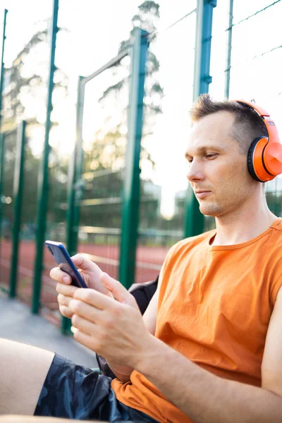 stock image fitness, sport and technology concept - young athlete man with headphones and smartphone listening to music outdoors