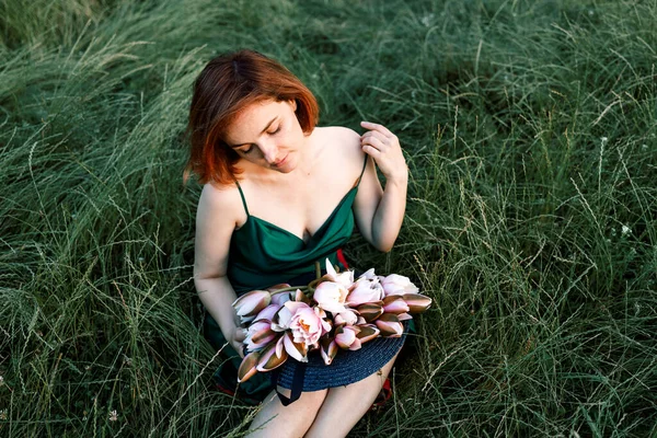 美丽的年轻女子手持水百合花的夏季生活方式肖像 坐在草地上 享受阳光吧 幸福与爱情的概念 呆滞的眼睛 — 图库照片