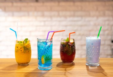 Kafenin ahşap masasında klasik kokteyller, portakal suyu, mojito ve mavi lagün ile buzlu sade kahve.