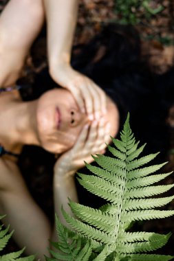 Genç bir kadın bir yaz günü çimlerin üzerinde yatıyor. Eğreltiotu yaprağının gölgesi. Yaz, mutluluk, doğal güzellik. Doğayı hissetmek. 