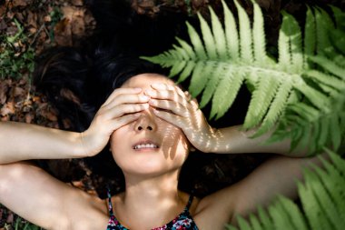 Genç bir kadın bir yaz günü çimlerin üzerinde yatıyor. Eğreltiotu yaprağının gölgesi. Yaz, mutluluk, doğal güzellik. Doğayı hissetmek. 