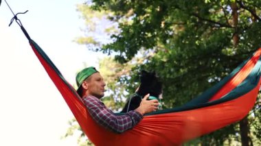 Yaz ormanlarında hamağın nazik salınımı bir adamı ve köpeği ormanlık ve gölle çevrili bir sükunete taşır. Yaz güneşinin tadını çıkarıyor, meditasyon yapıyor, rahatlıyor, tamamen rahat..