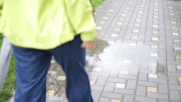 一个年轻的白人妇女的腿跳过了水坑 她快乐地享受着孤独与和平 穿着白运动鞋在雨中散步 — 图库视频影像