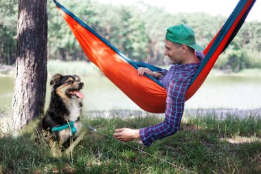 Köpekli bir adam yaz günü hamakta dinleniyor..