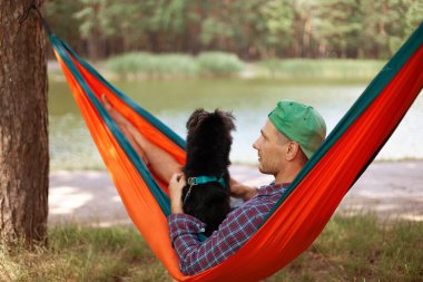 Köpekli bir adam yaz günü hamakta dinleniyor..