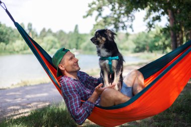 Köpekli bir adam yaz günü hamakta dinleniyor..