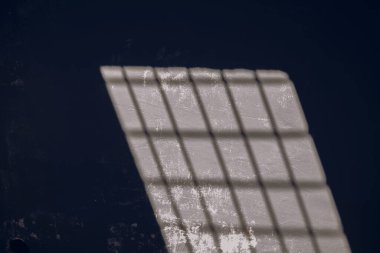 Karanlık hapishanedeki gri duvarda güneş ışığı ve gölge deseni var. Hapishane, hapishane ya da bodrum teması.