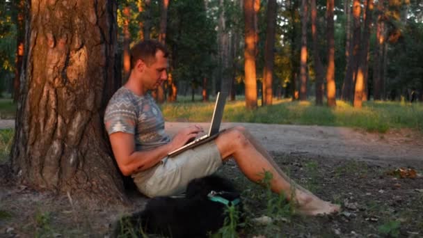 Junger Mann Mit Hund Arbeitet Mit Laptop Park — Stockvideo