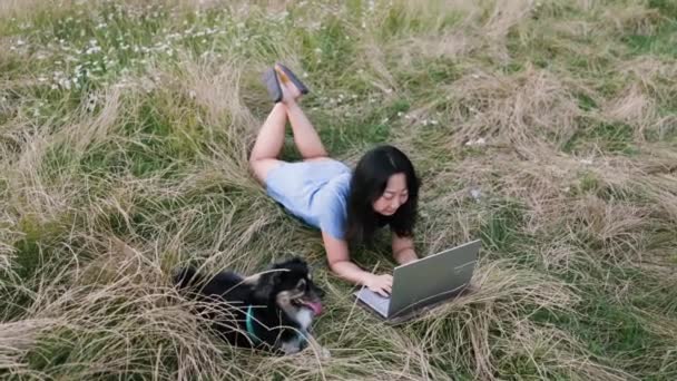 割下一只小狗躺在草地上 而旁边的亚洲姑娘则在干活 — 图库视频影像