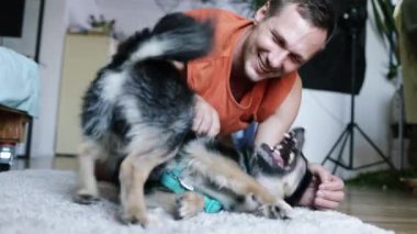 Bir adam ve küçük köpeği evde yerde yatıyor.