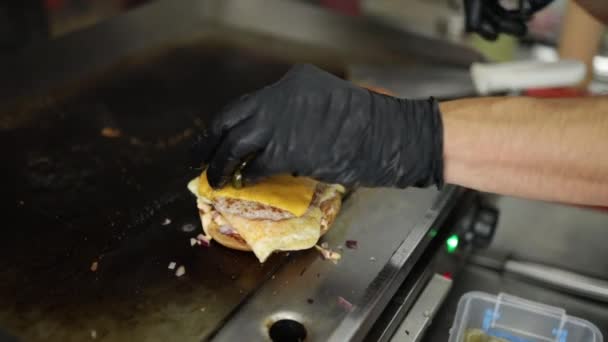 햄버거를 요리하는 장갑을 요리사 수평한 검은색 배경에 인식할 사진입니다 공간의 — 비디오