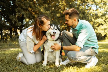 Güneşli bir günde parkta köpekli genç bir çift. Aşk konsepti