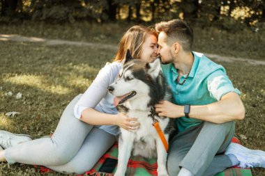 Güneşli bir günde parkta köpekli genç bir çift. Aşk konsepti