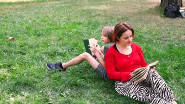 Mutlu anne ve oğlu parkta eğleniyor ve kitap okumaktan zevk alıyorlar. Anne ve çocuğu yaz bahçesinde dinleniyor.