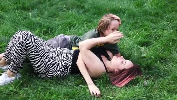 一个年轻的母亲和她的儿子在草地上的公园里的画像 他们拥抱着 微笑着 慈爱的母亲和她的儿子在公园里休息 — 图库视频影像