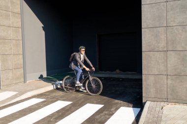 Yakışıklı, takım elbiseli genç bir adam sabah işe klasik bisikletiyle gidiyor. İş adamı bisikletle işe gidiyor. Çevre dostu ulaşım.