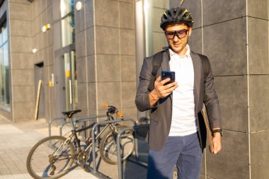 Şehir caddesinde akıllı telefon kullanan takım elbiseli yakışıklı bir iş adamı..