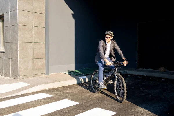 Handsome young adult man wearing suit riding his classic bicycle to work in the morning. Businessman going to work on bike. Eco friendly transport.