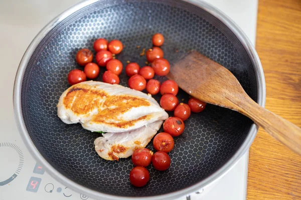 Grilled chicken fillet with cherry tomatoes on a frying pan.