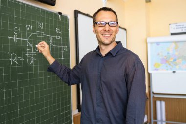 Öğretmen sınıfta tahtaya nasıl güvenileceğini öğretir. Gülümseyen adam sınıftaki bir sütundaki eklemeleri açıklıyor. Matematik öğretmeni aritmetik toplamları küçük çocuklara açıklar.