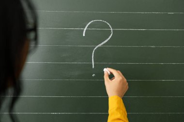 Tahtaların arka planında el yazısı soru işaretleri.