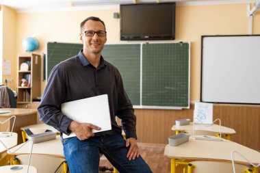 Sınıfta kendinden emin beyaz bir erkek öğretmenin portresi.