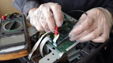 Bir teknisyenin elinin dijital multimetre kullanarak bir bilgisayar anakartının elektriksel voltajını ölçerken yakın plan görüntüsü. Bilgisayar donanımı bakım ve onarım kavramı.