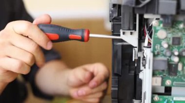 printer repair technician. A male handyman inspects a printer before starting repairs in a client's apartment.