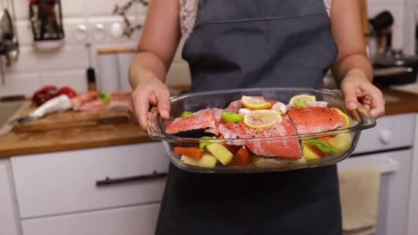 食品和人的概念 妇女在家里厨房的烤箱里用蔬菜烹调鲑鱼鱼 — 图库视频影像