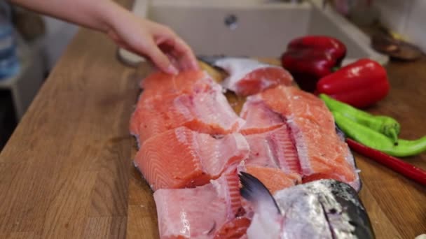 女性は木製の板に赤い魚をカットします キッチンでサーモンを切るシェフ — ストック動画