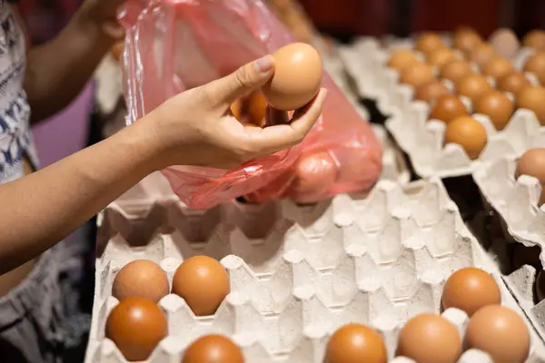 Close up of young woman hands selecting egg in supermarket.
