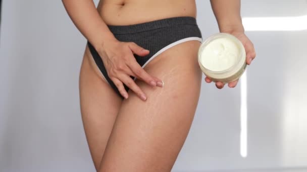 身体上有拉伸痕迹和蜂窝 穿内裤的女人 腿上涂润肤护肤霜 站在白底时使用抗蜂窝乳液或防晒霜 — 图库视频影像