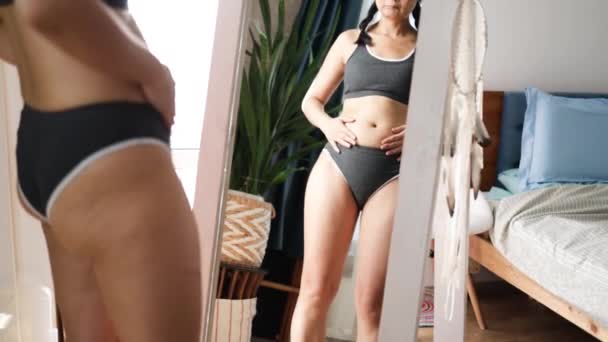 アジア人は鏡の前で女性を監督し 彼女の体を見ている 過剰な腹脂肪 不健康なライフスタイル ダイエットコンセプト — ストック動画