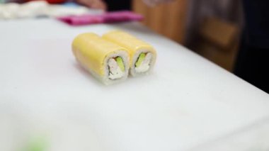Evde suşi yapmak, karides ve peynirli rulo kesmek, ev yapımı suşi, seçici odaklanma.