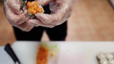 Geleneksel Japon yemekleri. Yakın plan. Suşi şefi sosla dekore eder taze pişmiş suşi ruloları, güzel bir tabakta servis edilir. sanat restoranda hizmet veriyor..