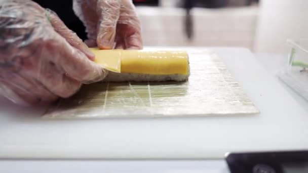 厨师正在餐厅厨房里做日本寿司 厨师在一家日本餐馆用滚动垫子做寿司 厨师正在把奶酪放进日本寿司卷里 — 图库视频影像