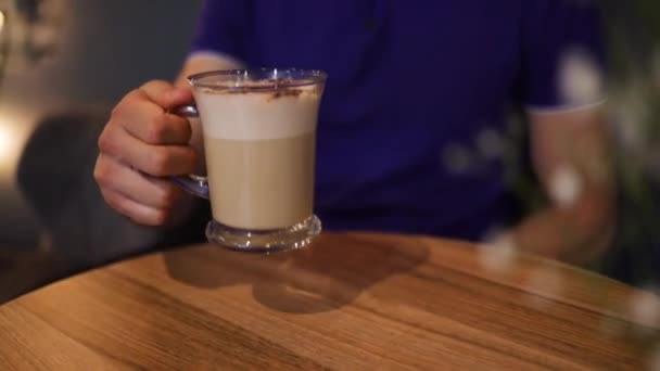 年轻的高加索人坐在吧台柜台上 在咖啡店里喝着拿铁咖啡 有信心的男人拿着咖啡杯 喝着香浓的热咖啡 — 图库视频影像