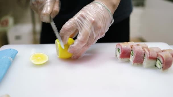 プロのアジア人シェフが伝統的な方法で寿司を準備しています シェフはレモンで上に寿司を飾る — ストック動画