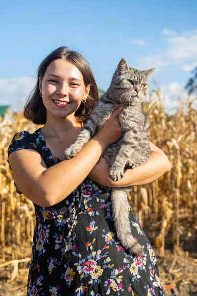 Portrait of a beautiful young woman with a cat in a cornfield