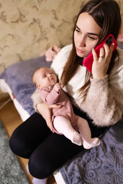Mom calls the doctor on the phone, worried about her baby, crying desperately at home