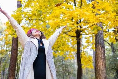 Merhaba Ekim. Şehir parkında eşarplı, kırmızı şapkalı mutlu bir kadın..