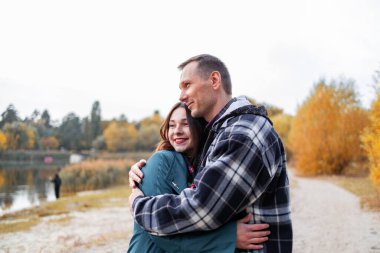 Genç Sevimli Kadın Hugs erkek. Sonbahar açık. Lovers Park'ta yürüyordunuz. Çekici komik çift. Ormandaki lovestory. Erkek ve kadın. Parkta şirin severler. Aile kavramı. Mutlu çift.