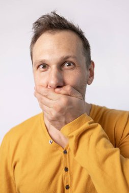 Beyaz arka planda, şok olmuş yüz ifadeleri olan genç bir adamın portresi..