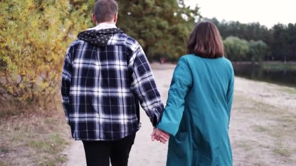 年轻夫妇手牵手在秋天的城市公园里散步 享受着在一起的时光 — 图库视频影像