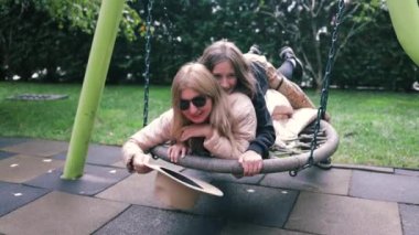 Anne salıncağı itiyor ve neşeli çocuk gülüyor, mutlu aile, çocuk sonbahar çocuk parkında salıncakta oynuyor, çocuk eğlencesi dışarıda, hafta sonları küçük insanların hayatı, çocukluk hayalleri uçuyor.